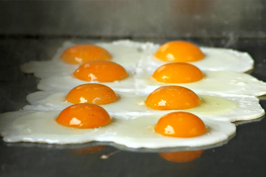 Eight eggs being fried on a pan